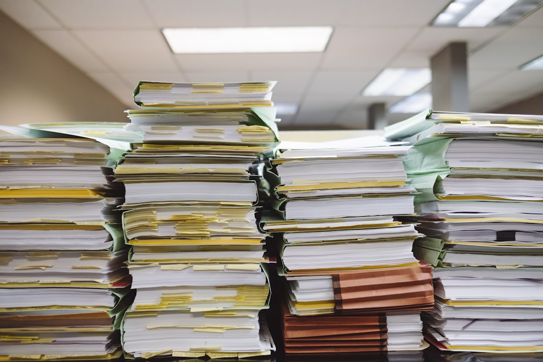 Stacks of paper documents and file folders — the old way of managing accreditation evidence