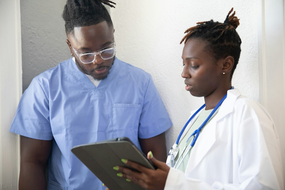 Two clinicians in scrubs reviewing a clipboard together, representing the clinical documentation an SPE tracks
