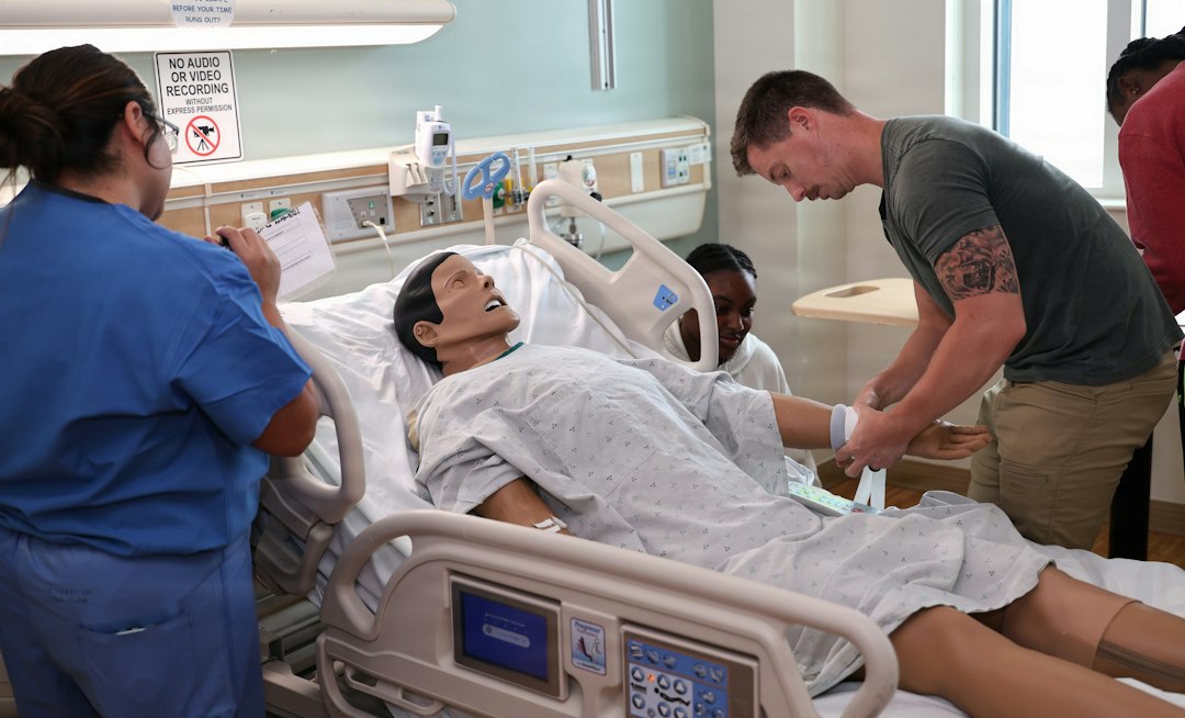 Students practising clinical skills on a hospital bed simulator during a training exercise