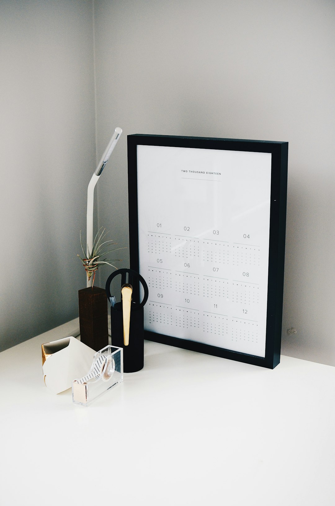 A framed monthly calendar on a white shelf