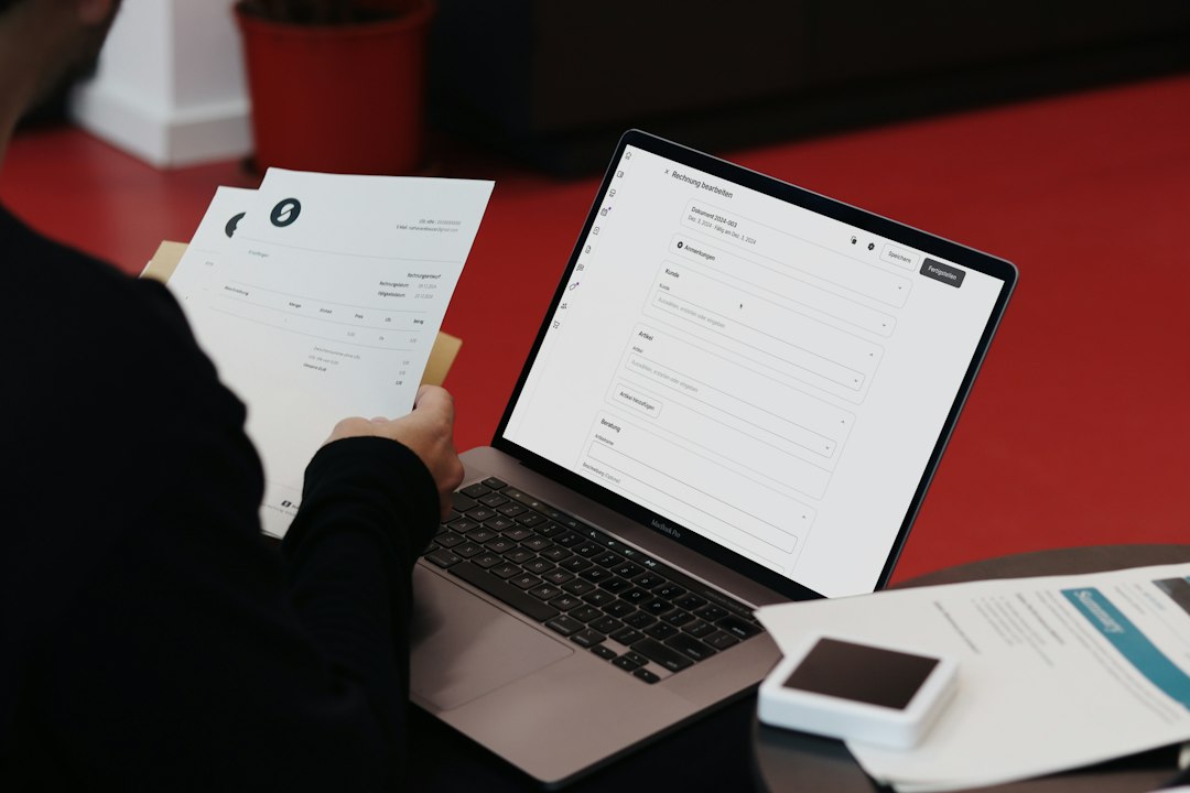 Clipboard of accreditation documentation, envelope and pencil beside a laptop