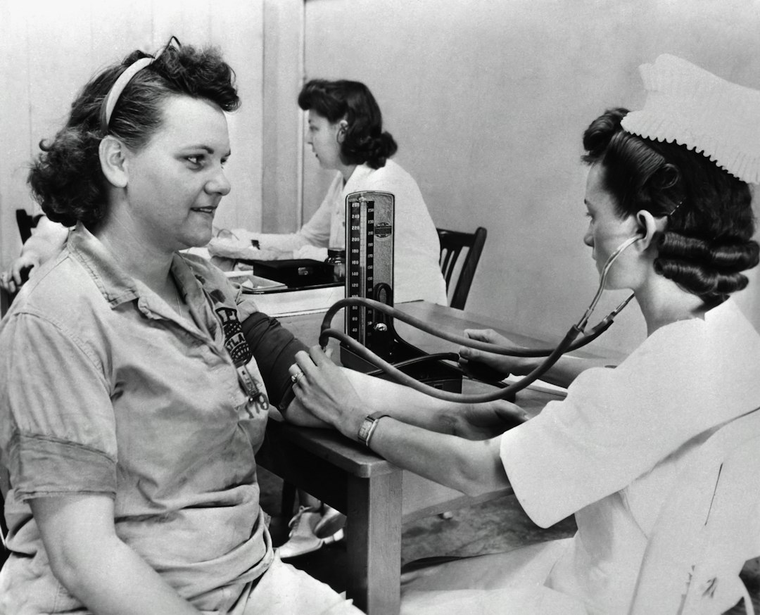 A student practicing a blood pressure check on a simulation mannequin in a hospital bed