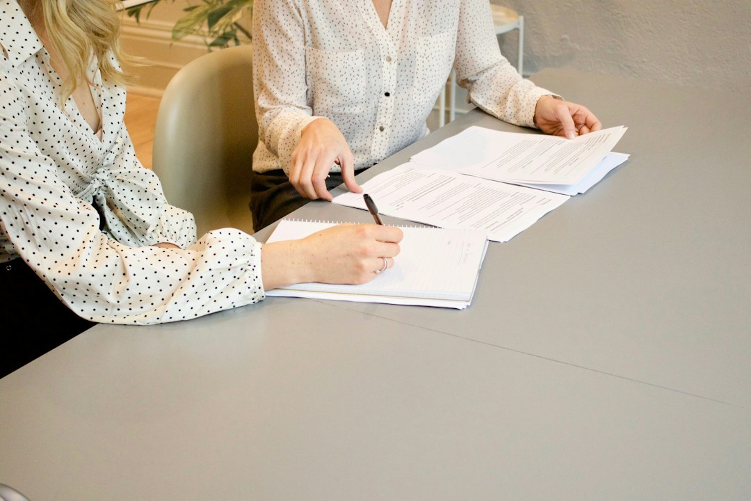 A coordinator and colleague reviewing the self-study document alongside a laptop