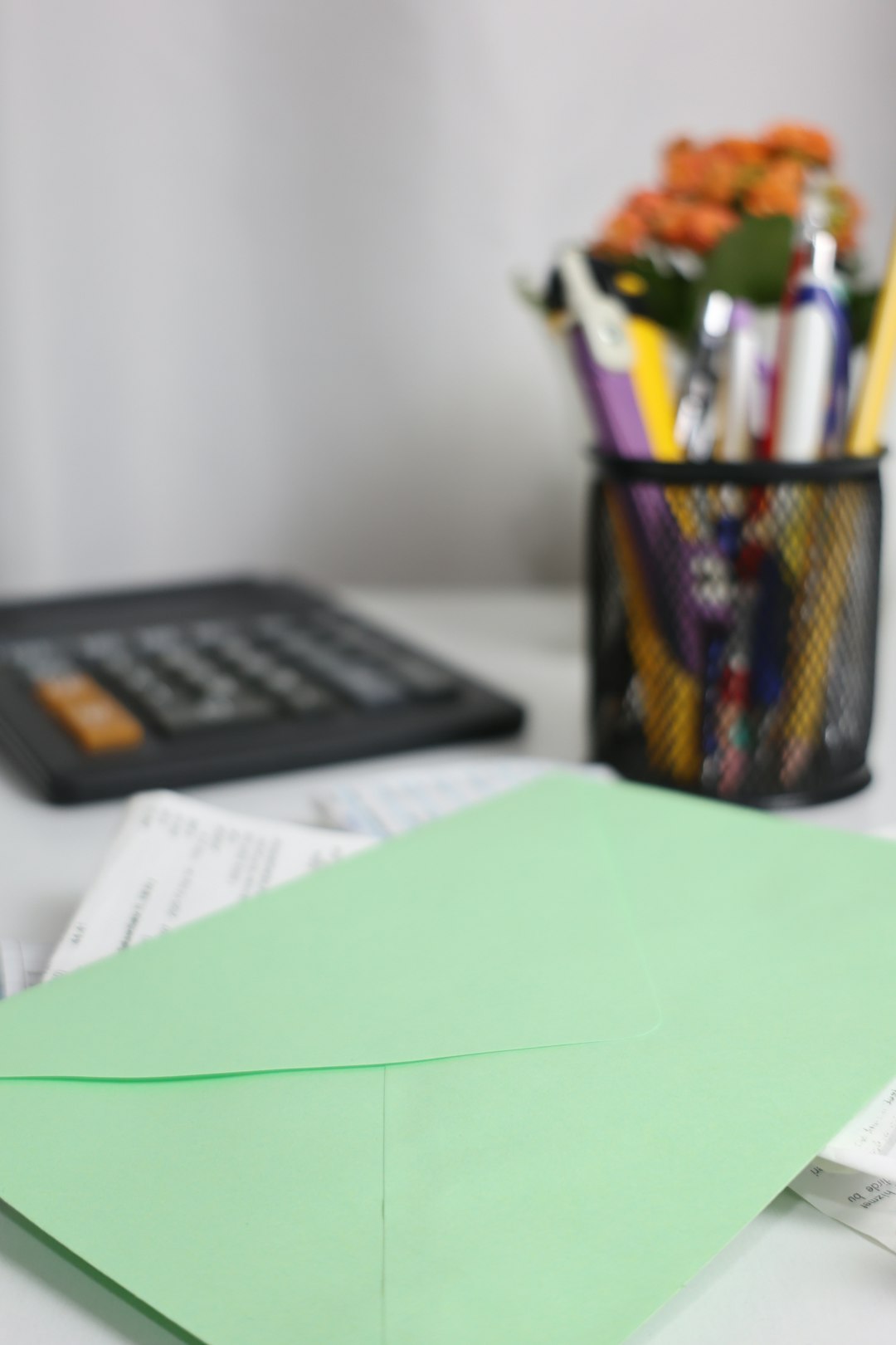A green envelope and papers on a desk beside a calculator