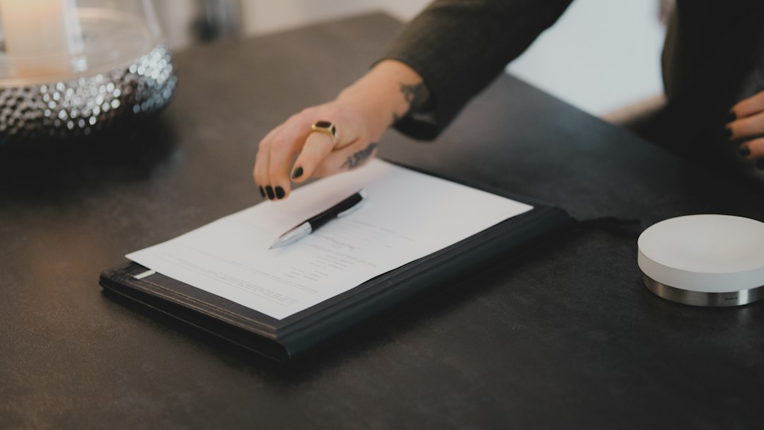 A hand resting a pen on a document over a folder, marking the completion of a systematic evidence review
