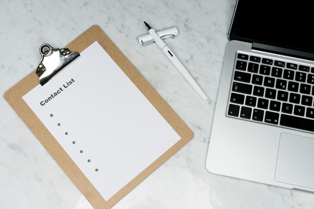 A curriculum change checklist clipboard beside a laptop on a desk