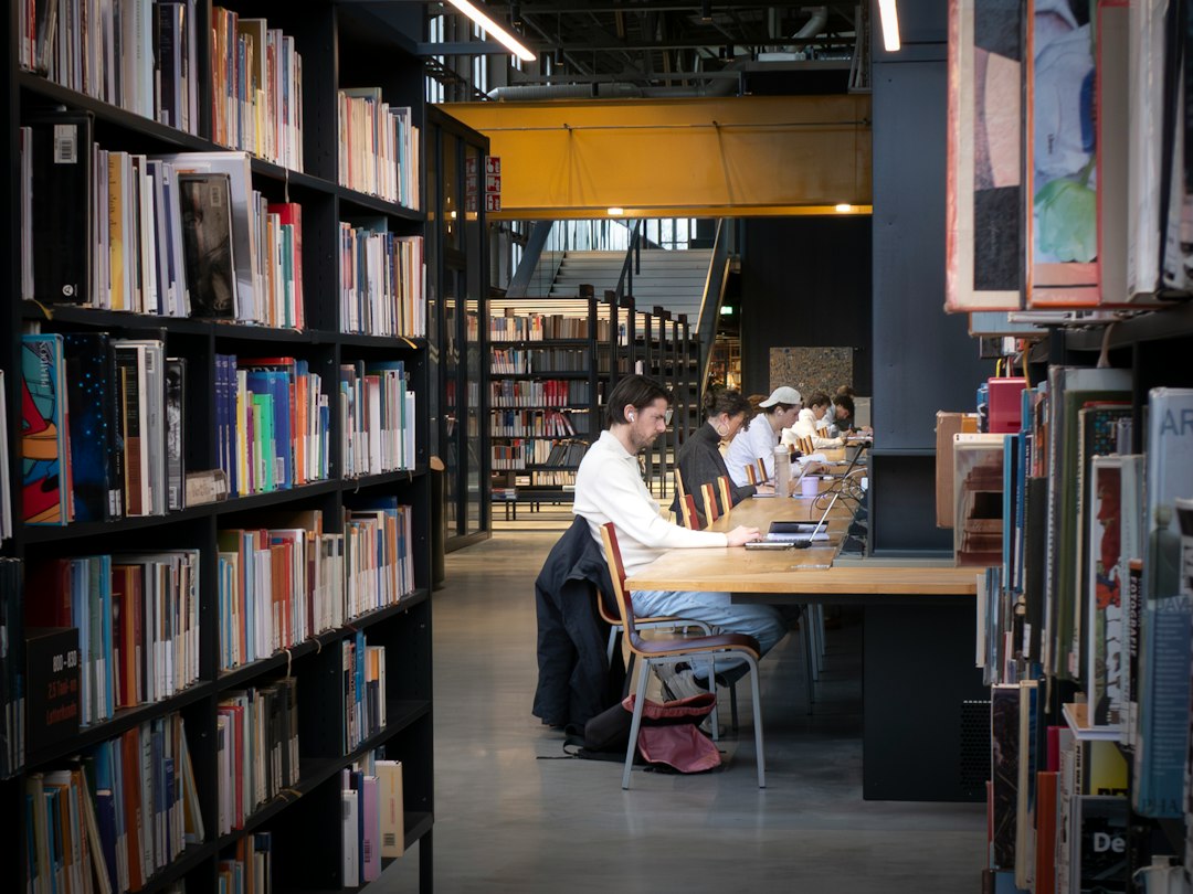Students working at tables in a modern library between bookshelves