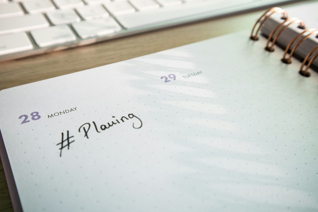 A spiral notepad with a handwritten planning note on a desk